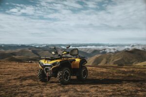 Gelbes Allrad-Quad Guardian 500 auf einem Bergplateau mit weitem Blick auf Berge und Wolken