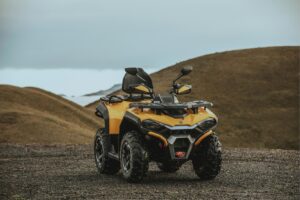 Allrad-Quad Guardian 500 mit robustem Design, Sitz und Gepäckträger, stehend auf Schotter vor Hügeln